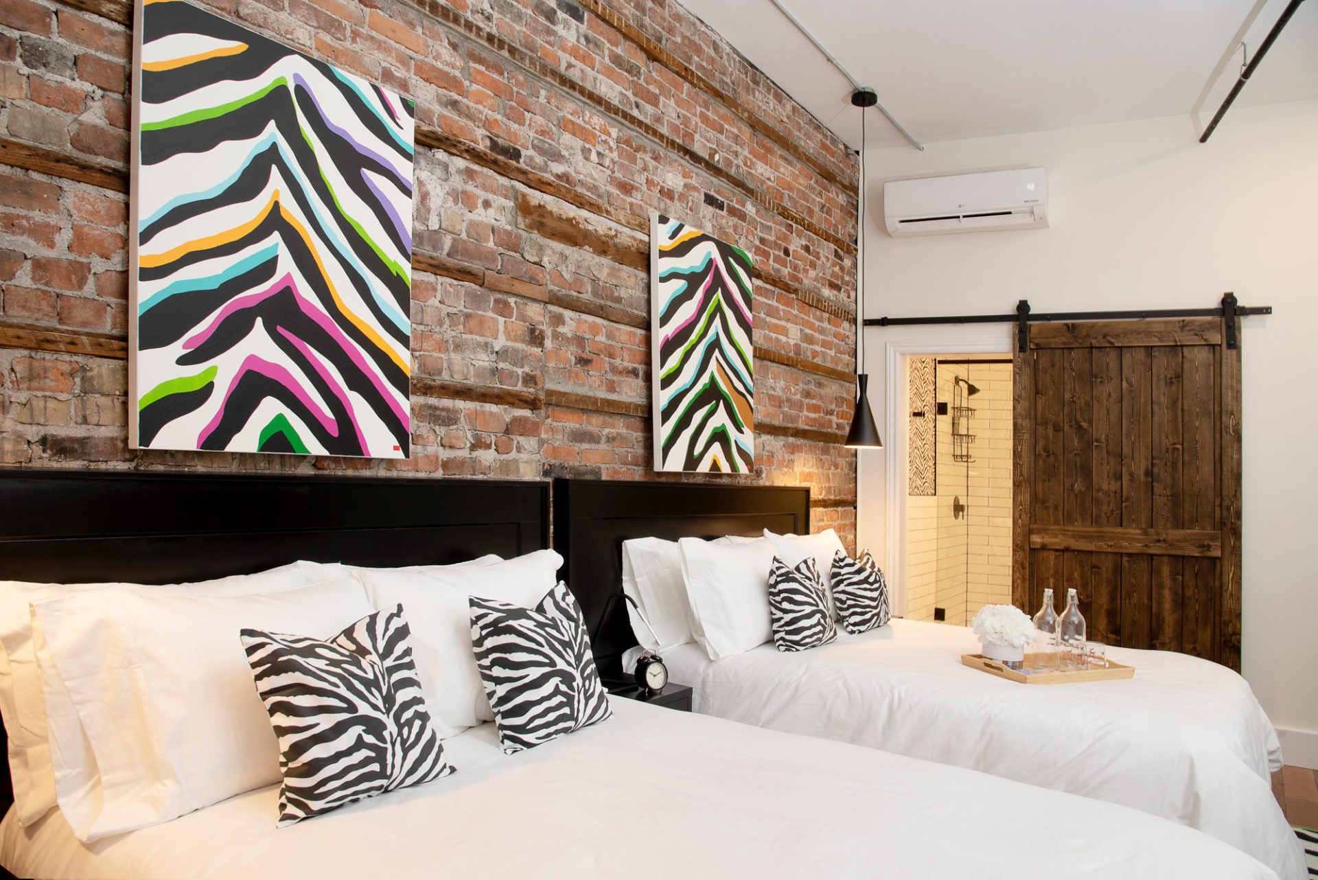 Two beds in a room with a sliding barn door into the bathroom