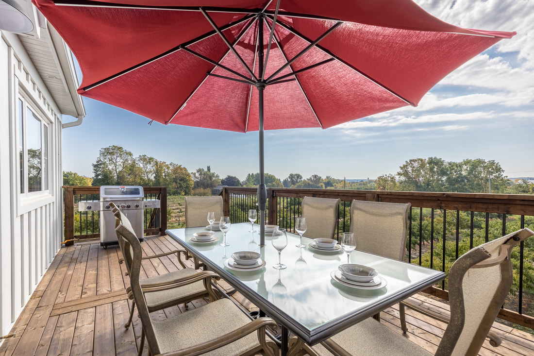 A balcony with a patio table and umbrella overlooking trees