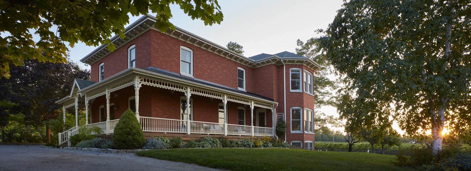 A large red brick house sitting on top of a lush green field