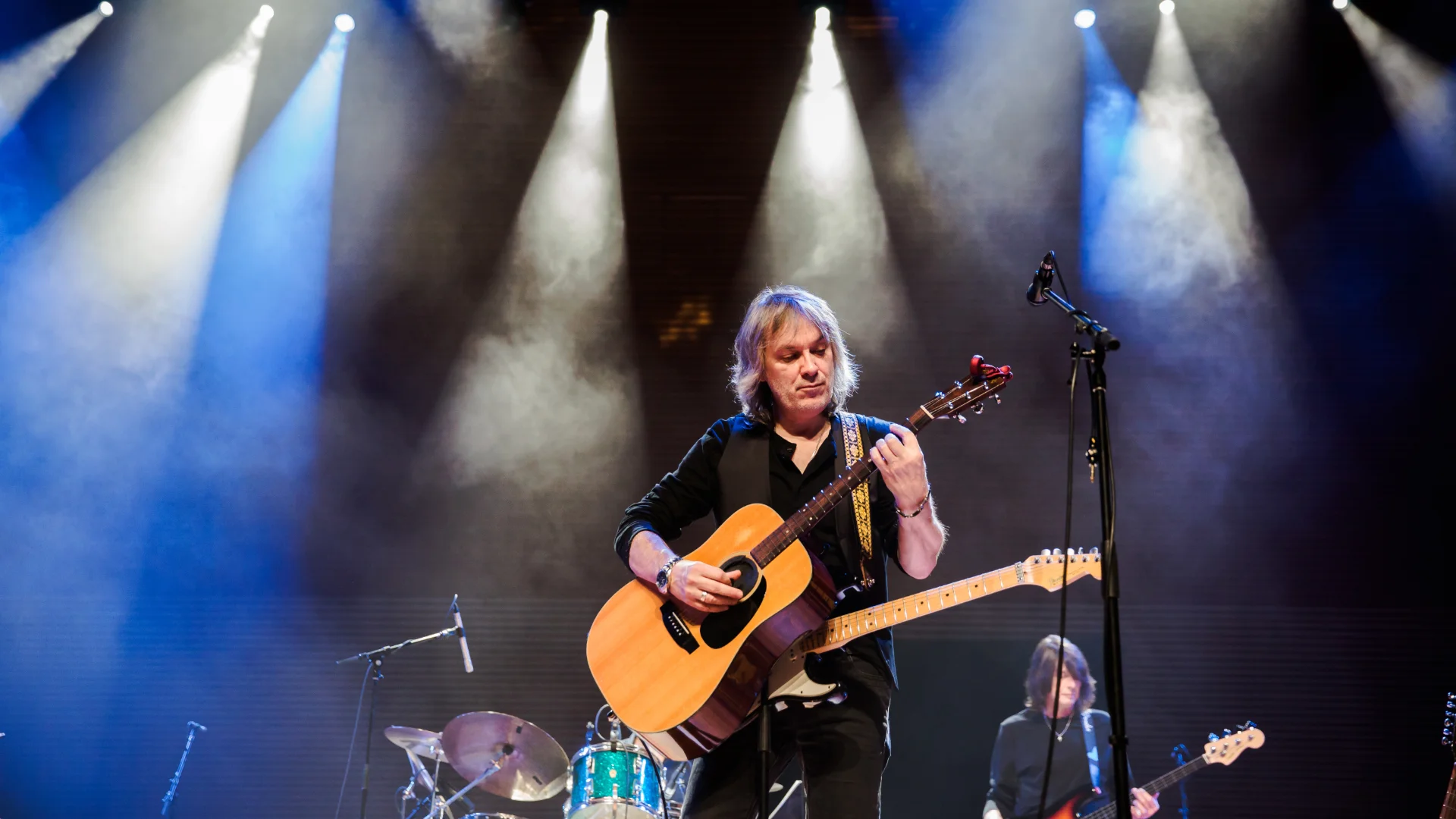 A man playing a guitar on stage with other musicians