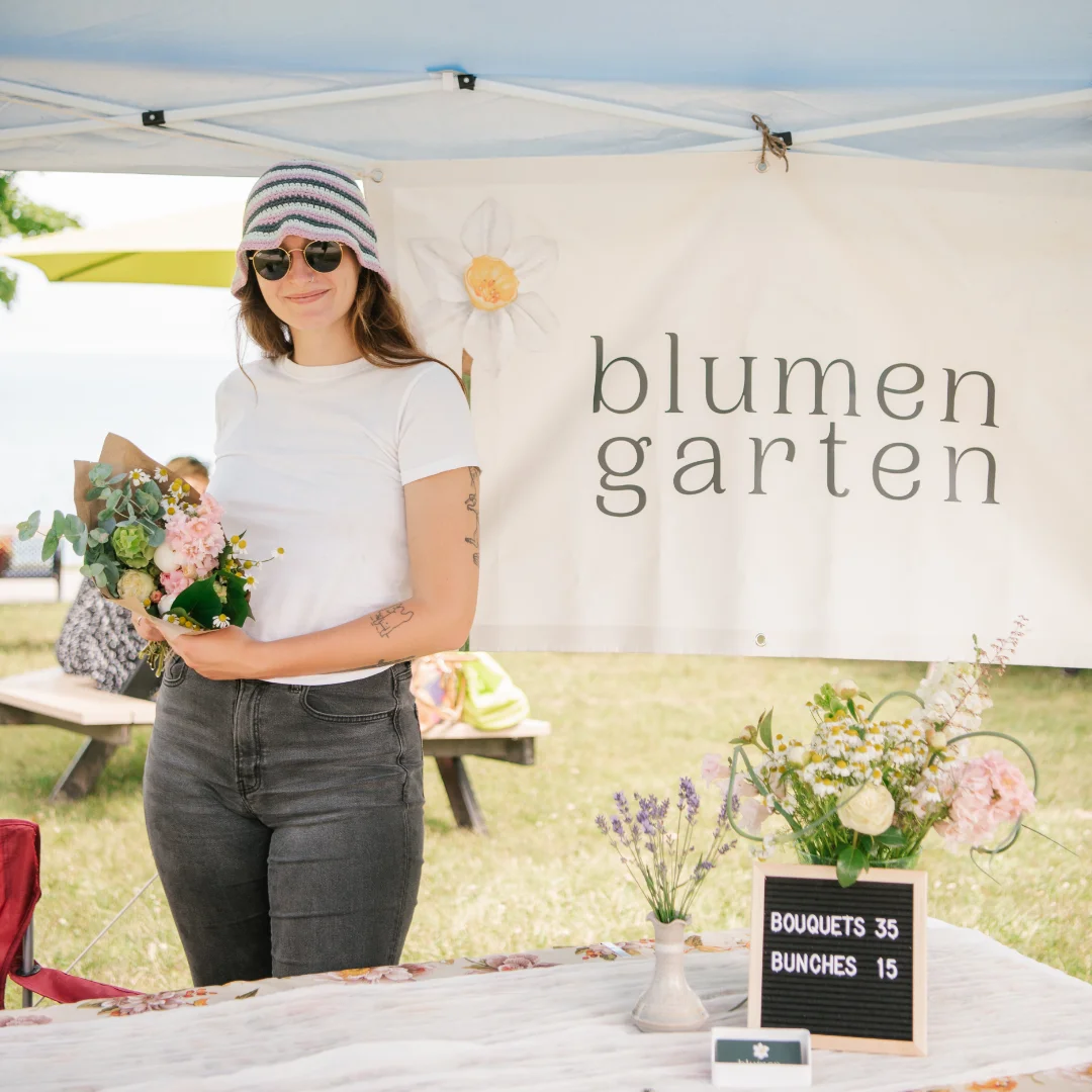 A woman holding a bunch of flowers in front of a sign