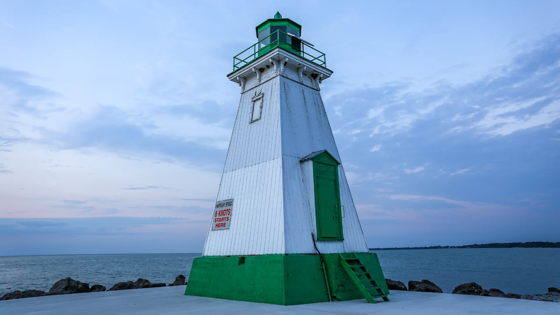 A white and green light house next to the ocean